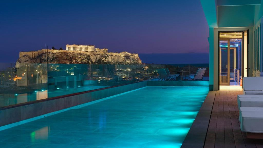 An outdoor infinity pool at night, with an incredible view of the Acropolis in Athens.