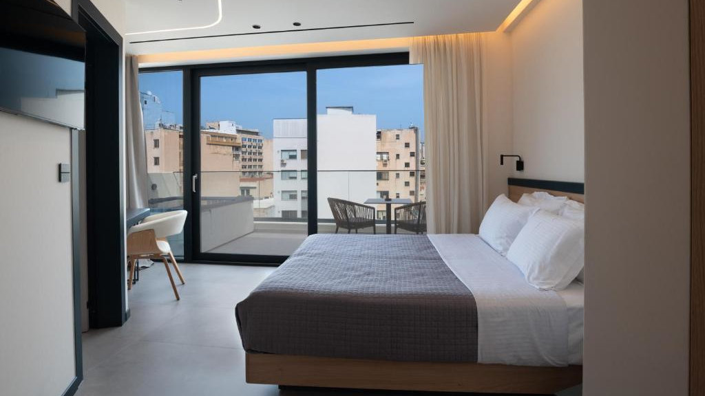 A hotel room looking over the bed to the balcony with a private jacuzzi.