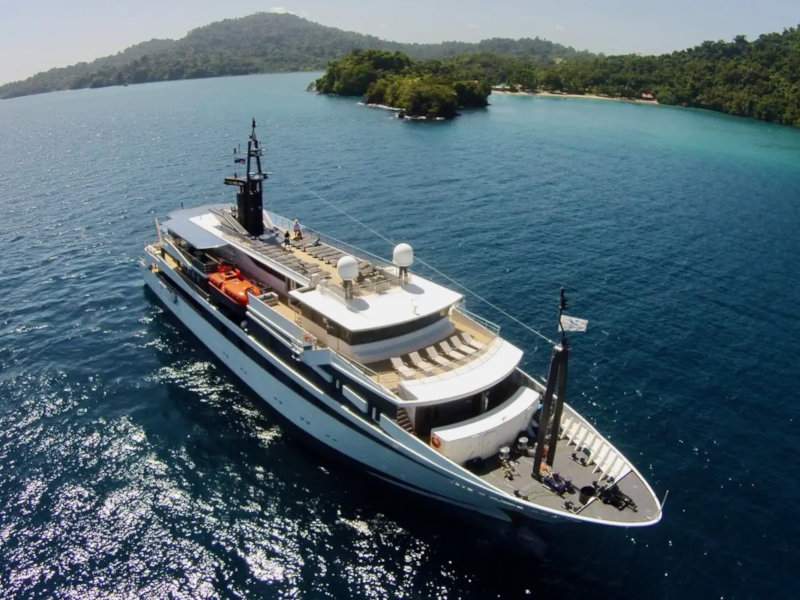 A luxury yacht seen from above on the water in the sun.