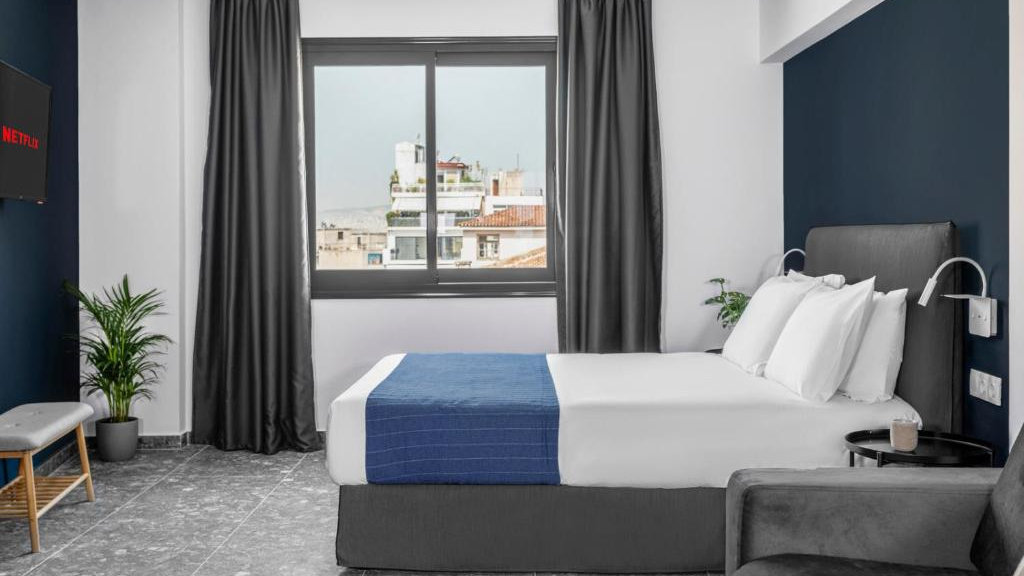 A chic hotel room with navy blue accents and a charming view over Athens from the window.