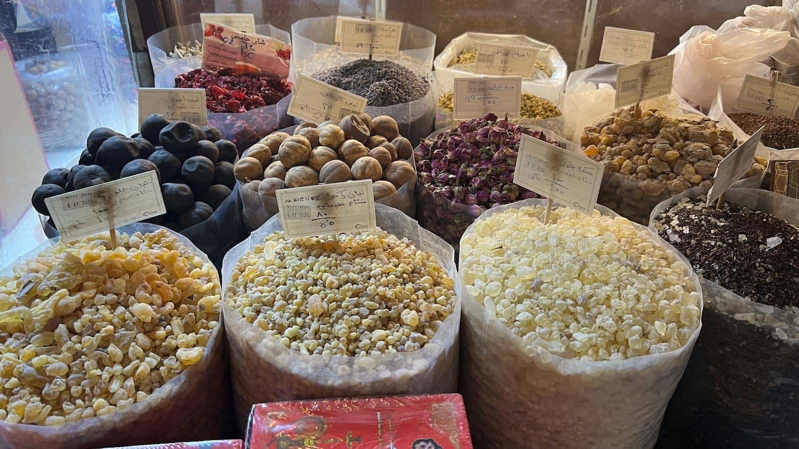 A variety of fruits and spices in clear containers at a market.