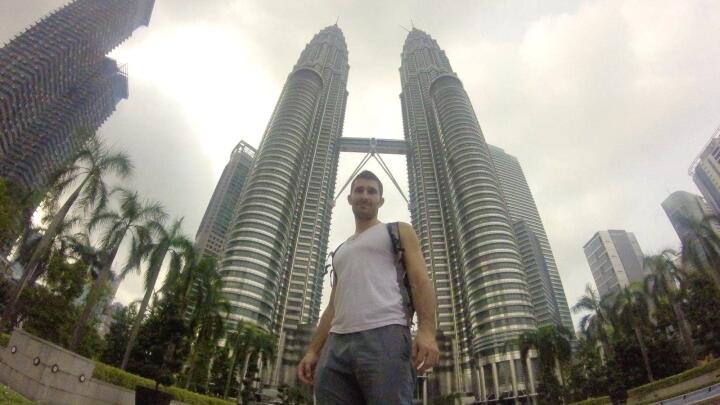 A very low angle shot of Stefan standing in front of two tall towers.