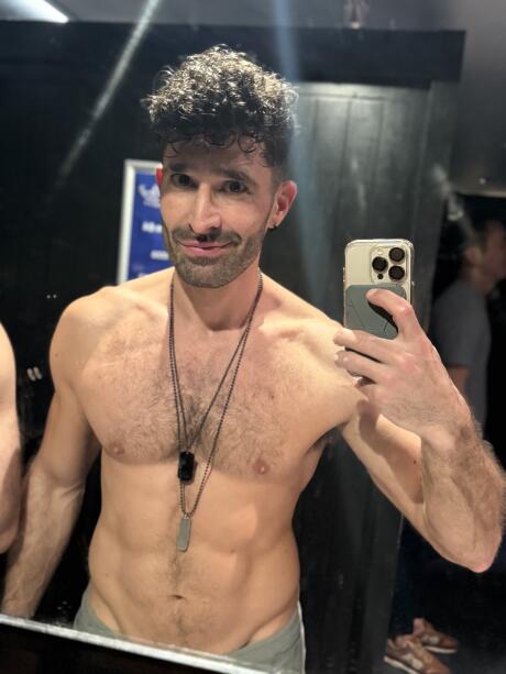 Stefan taking a selfie in a bathroom mirror while wearing nothing on top.