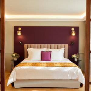 A grand hotel bed with magenta walls and pillows.