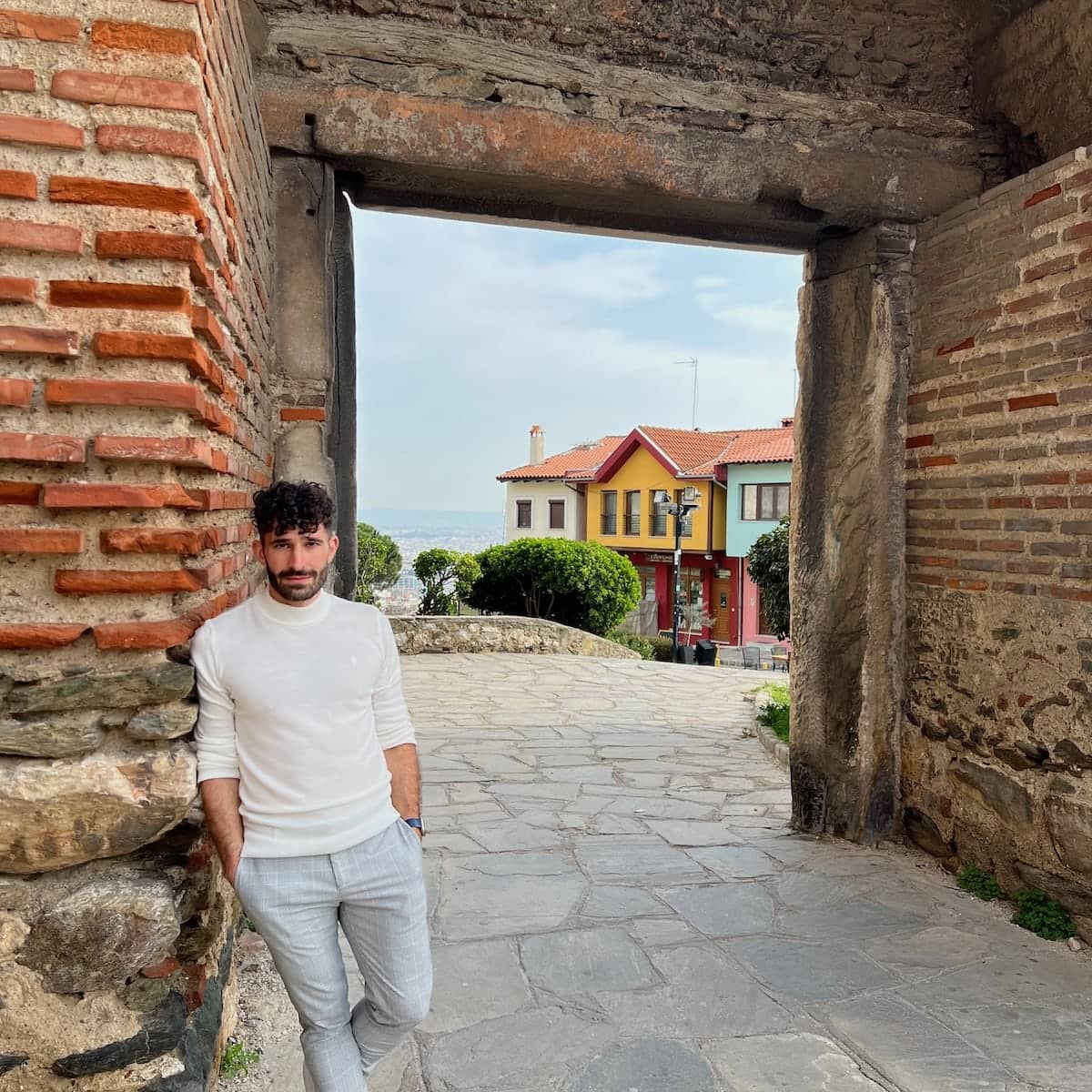 Stefan leaning against a wall with an arch leading to colorful houses in the background.