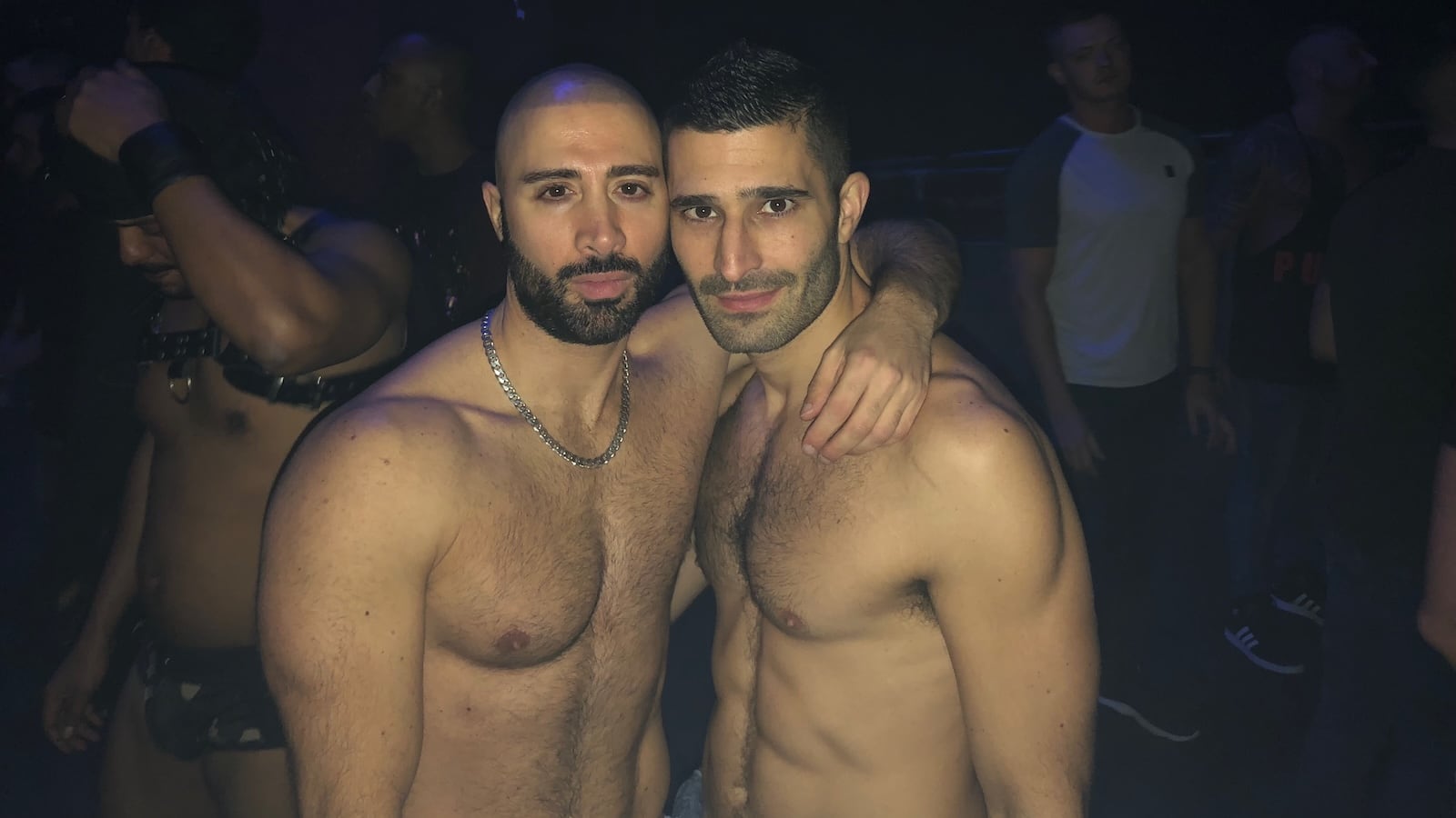 Stefan and a friend both posing topless in a darkened club,