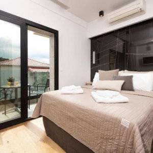 A hotel room with black accents and a glass door leading to a private balcony.