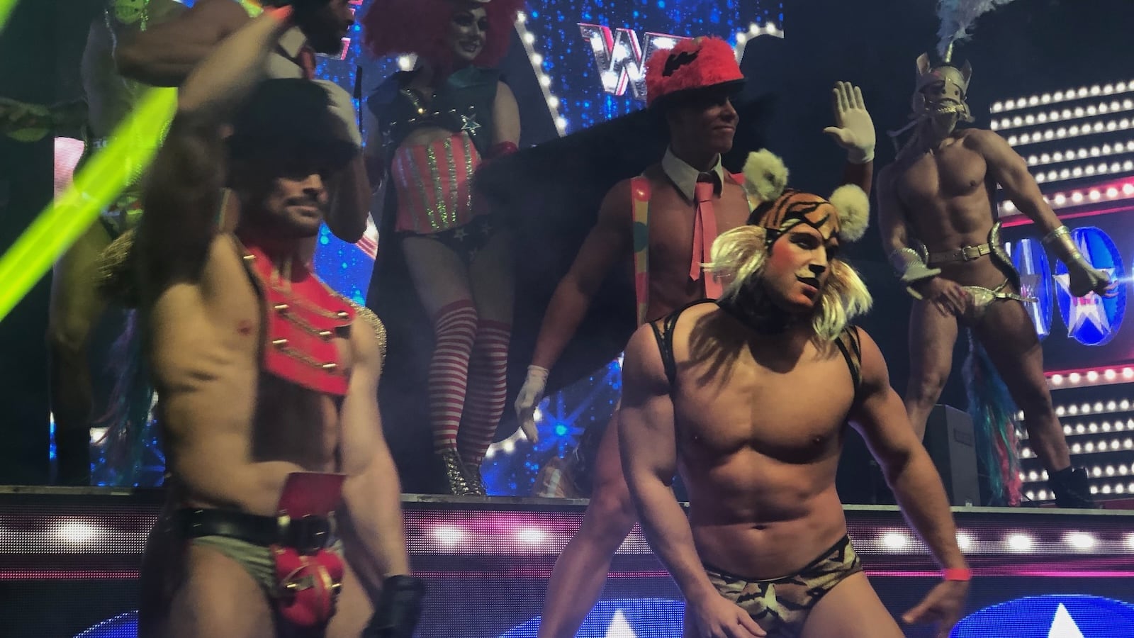 Topless men in a stage in costumes dancing.