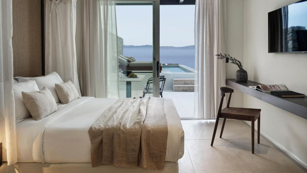 A chic hotel room showing the view across the bed out to the private balcony and plunge pool.