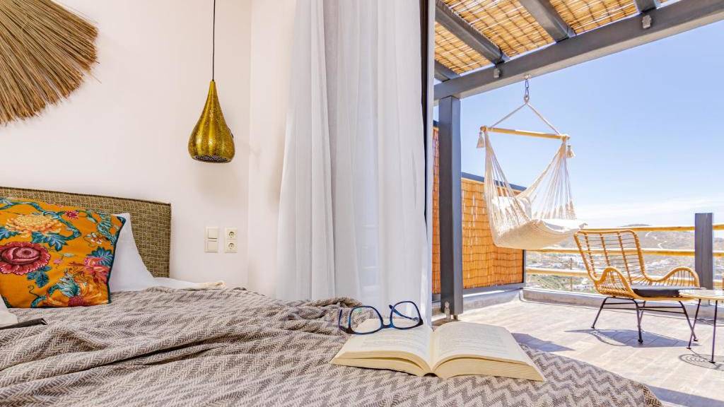 A view from a hotel bed looking onto a balcony with a hammock chair on a beautiful sunny day.