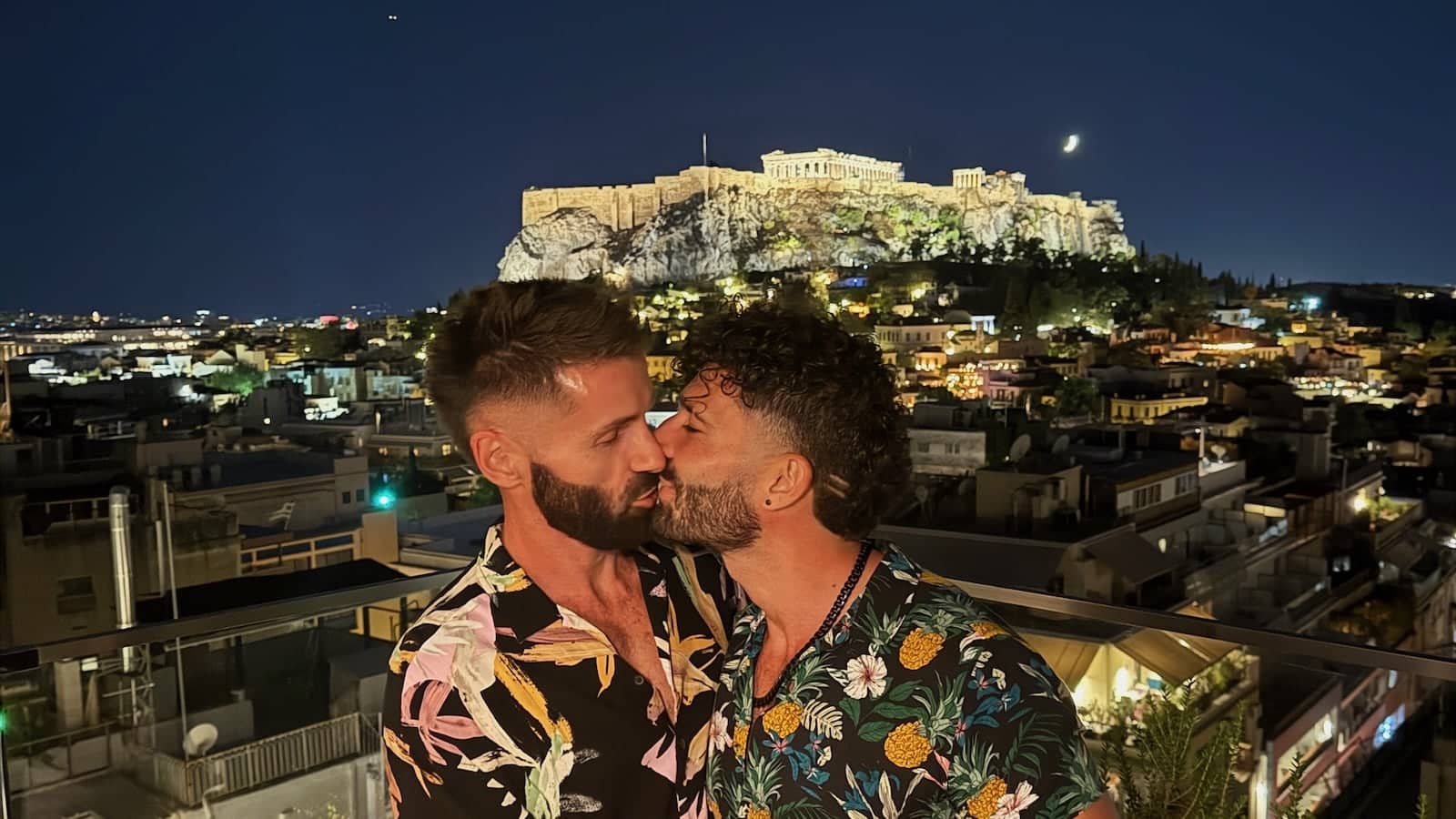 Gay couple Stefan and Seby kissing by the Acropolis in Athens at night.